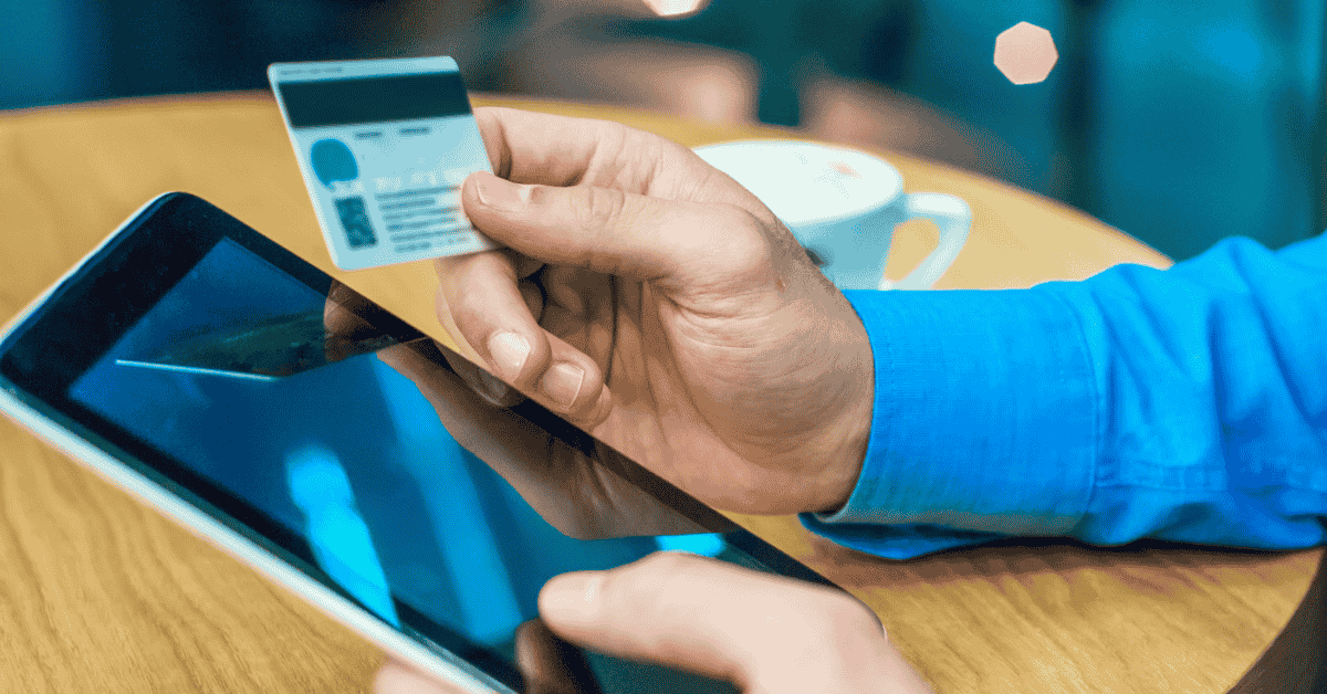 A person holding a credit card in front of a laptop while typing, representing online payment or e-commerce.