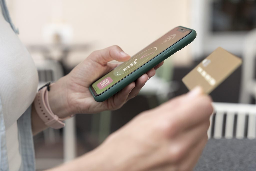 A person holding a smartphone with a payment app open and a credit card in the other hand, illustrating contactless or mobile payment.