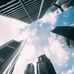Low-angle view of modern skyscrapers against a blue sky with clouds, symbolizing business, finance, banks and corporate success.
