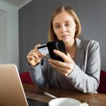 Woman making an online payment with a credit card on smartphone at home